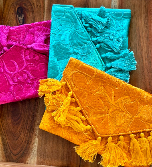 Three colorful fabric bags with tassels on a wooden surface